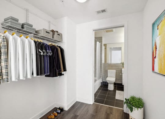 a closet with clothes and a bathroom with a toilet