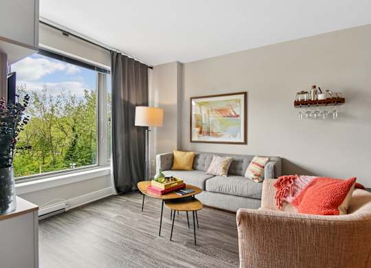 A living room with a grey couch, a brown chair, a coffee table, and a painting on the wall.