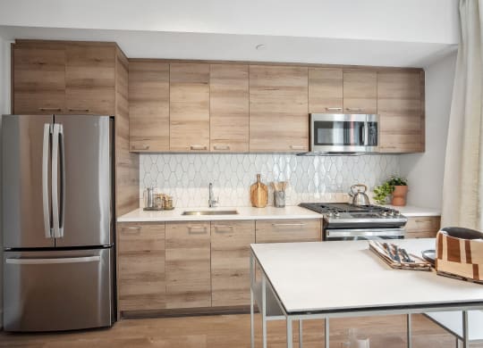 a kitchen with wooden cabinets and a stainless steel refrigerator at The Grace and Reva, Arlington, Virginia