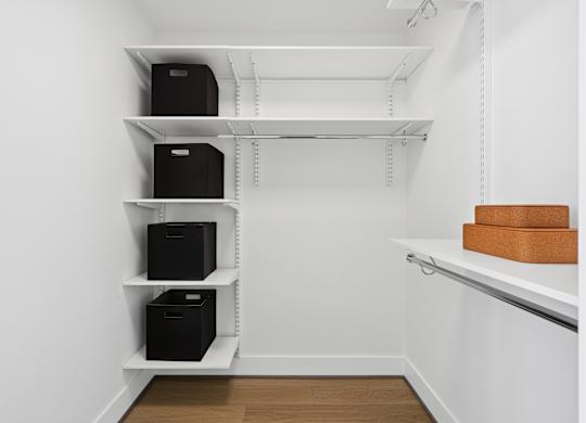 A white shelving unit with black boxes and brown boxes on top.