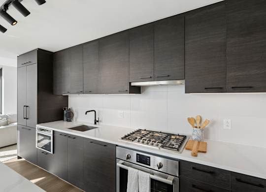 A modern kitchen with dark wood cabinets and stainless steel appliances.