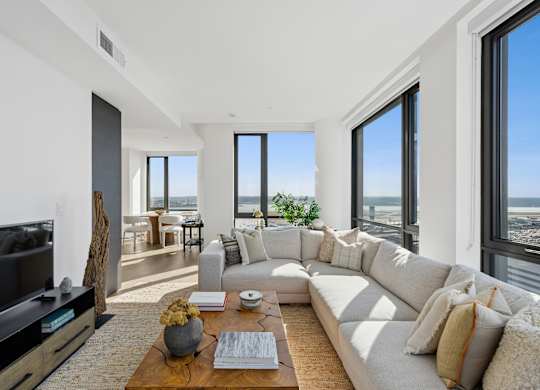 A modern living room with a large white sofa and a flat screen TV.