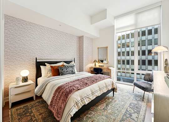 A bedroom with a large bed and a window overlooking a building.