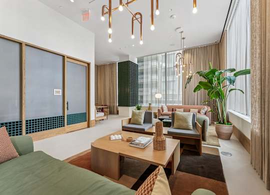 A lobby with a green sofa and a wooden coffee table.
