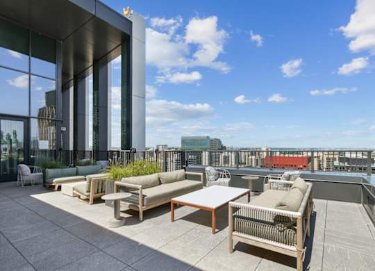 A rooftop patio with a table and chairs overlooking a city skyline.