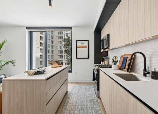 A modern kitchen with wooden cabinets and a large window.