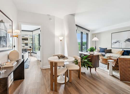 A modern living room with a dining area and a kitchen in the background.