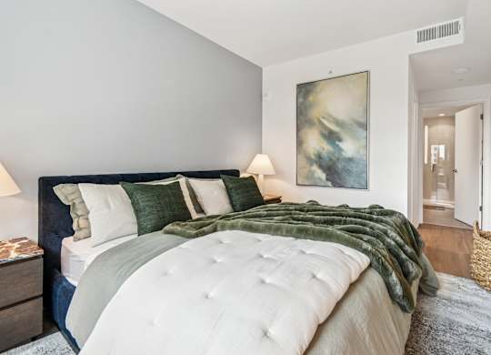 A bedroom with a large bed and a painting on the wall.