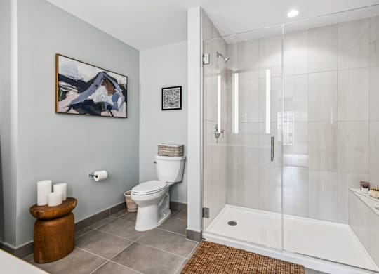 A bathroom with a toilet, a towel, and a painting on the wall.