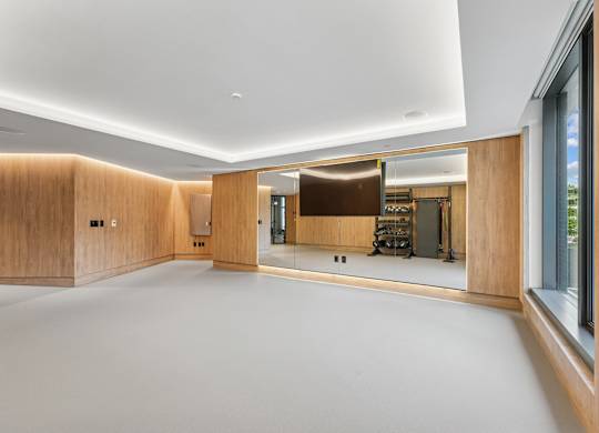 A spacious room with wooden walls and a large mirror on the wall.