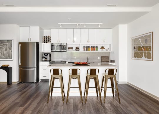 a kitchen with white cabinets and a bar with three bar stools
