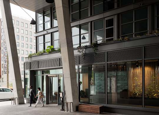 A modern building with a glass facade and a couple walking in front.