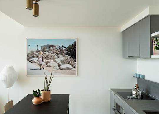 A modern kitchen with a black countertop and a framed photograph of a house on the wall.