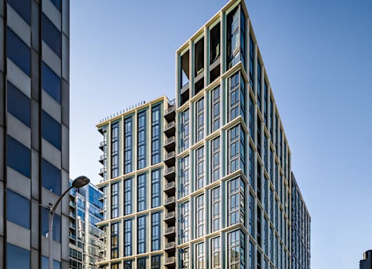 A tall building with many windows is located on a street corner.