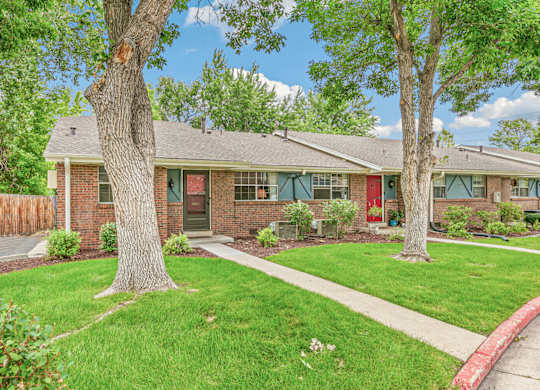 A house with a red door and a green lawn.