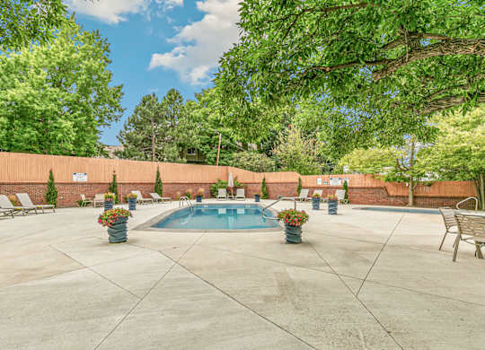 A pool surrounded by a concrete patio and trees.
