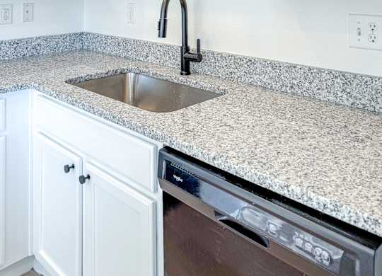 A kitchen with white cabinets and a granite countertop.