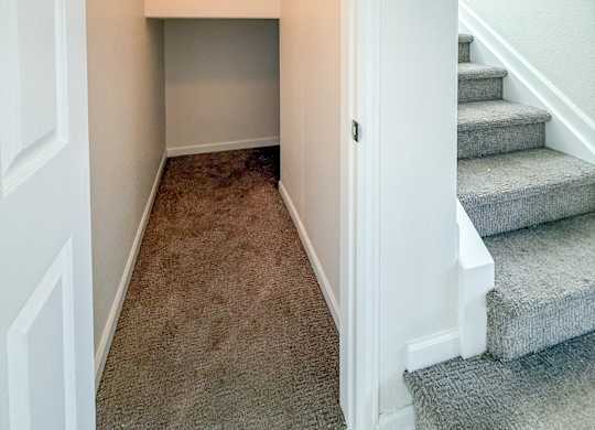A hallway with a staircase and a light on the wall.