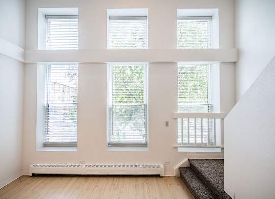 A room with three windows and a staircase.