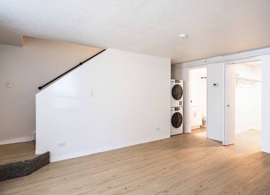 A room with a white wall and a door leading to another room.