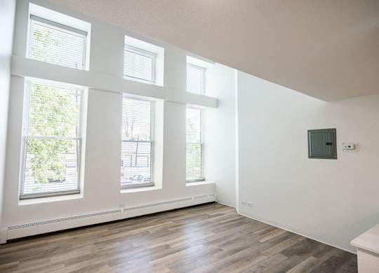 A room with wooden floors and three windows.