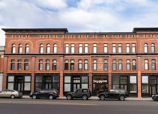 A red brick building with cars parked in front.