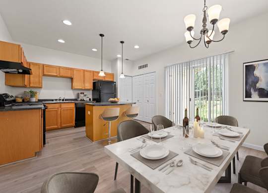 A modern kitchen with a dining table set for two.
