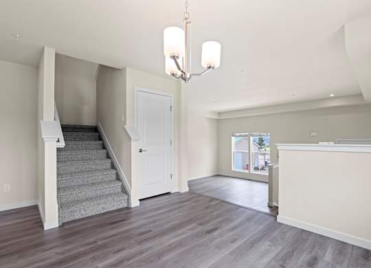 Large, empty room with a staircase and a chandelier at The Townhomes at Pine Drive, Parker, CO
