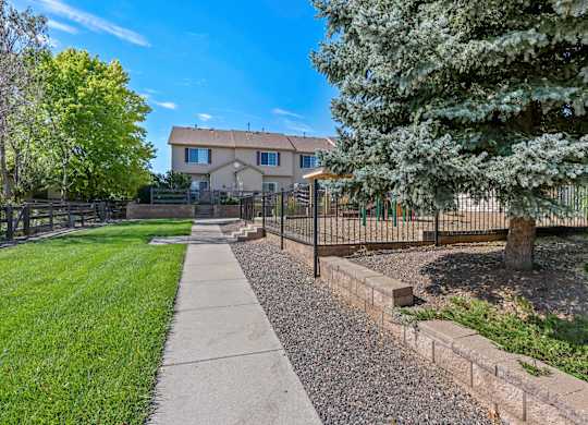 A house with a fence and a tree in front of it.