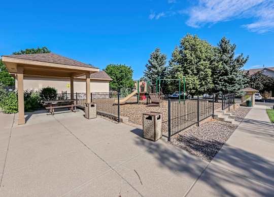 A playground with a swing set and a gazebo.