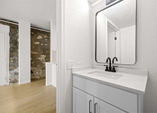 A bathroom with a sink, mirror and wooden floors at Tallmadge Lofts in Denver, Colorado