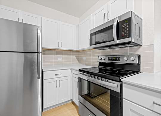 A kitchen with a refrigerator, microwave, oven and cabinets at Tallmadge Lofts in Denver, Colorado