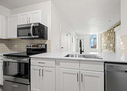 A kitchen with white cabinets and appliances at Tallmadge Lofts in Denver, Colorado
