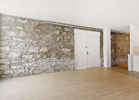 A room with a stone wall and wooden flooring at Tallmadge Lofts in Denver, CO