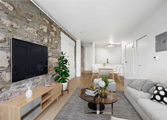 A living room with a stone wall and a flat screen TV at Tallmadge Lofts in Denver, CO