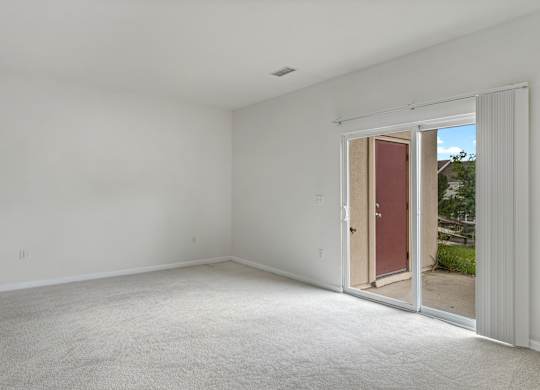 A room with a carpeted floor and a door leading outside.