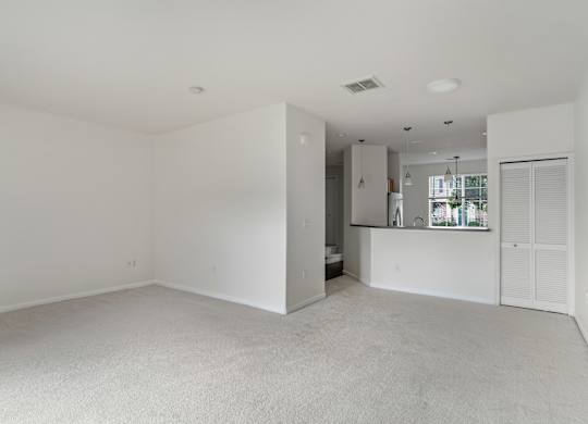 A large, empty room with white walls and carpeted floor.