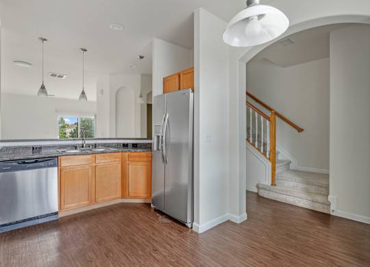 A kitchen with a refrigerator and a stainless steel dishwasher.