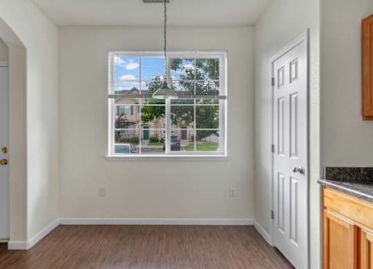 A room with a window showing a view of houses and trees.