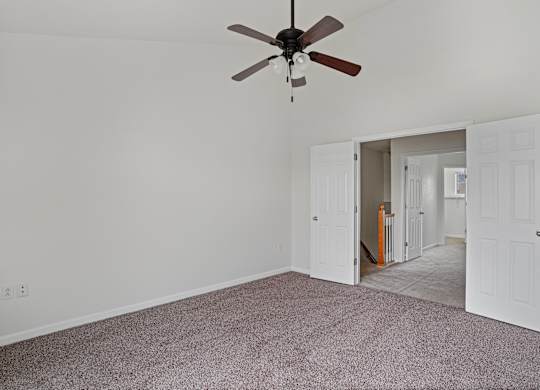 A room with a ceiling fan and carpeted floor.