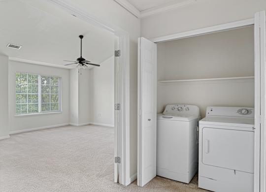 A room with a ceiling fan and two washing machines.