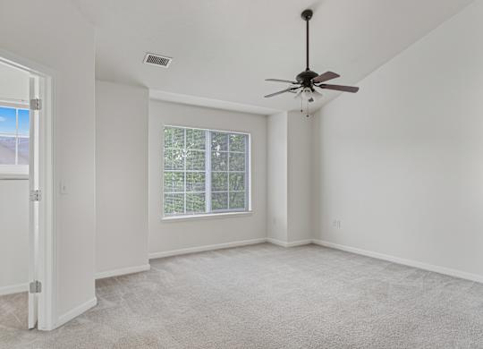A room with a ceiling fan and a window with blinds.
