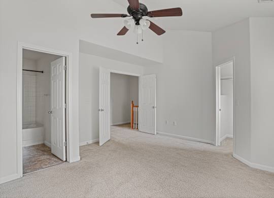 A room with a ceiling fan and carpeted floor.