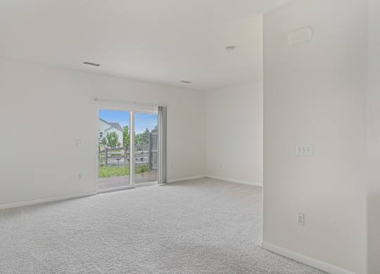 A white room with a sliding glass door leading to a patio.