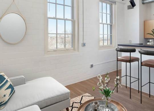 A living room with a white couch and a coffee table with a vase of flowers on it.