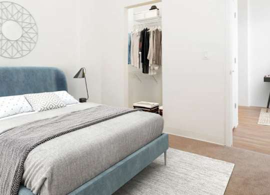 A bedroom with a bed, a lamp, a rug and a wardrobe.