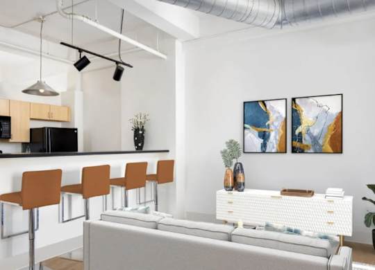 A modern living room with a grey sofa, a bar area with orange chairs, and two abstract paintings on the wall.