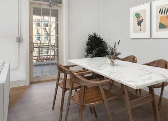 A dining room with a marble table and wooden chairs.
