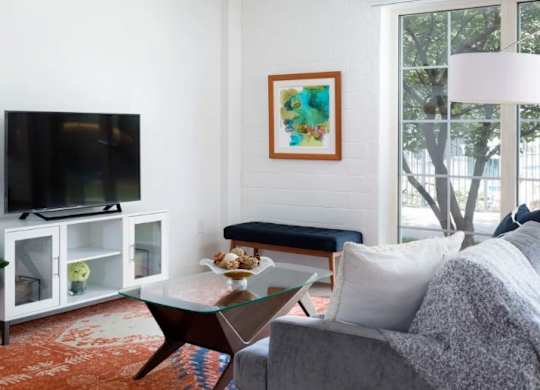 A living room with a television, a couch, and a painting on the wall.