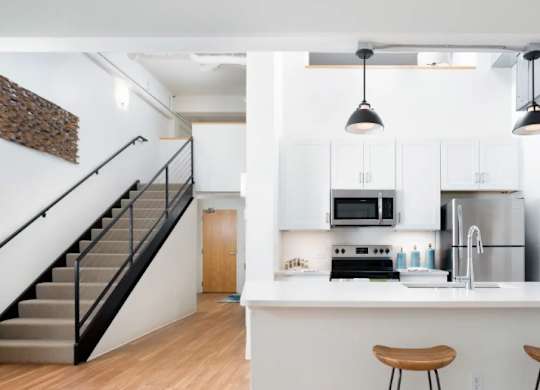 A kitchen with white cabinets and a bar area with stools.